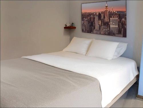 - un lit blanc dans une chambre avec une photo sur le mur dans l'établissement Appartement Cosy à 2 pas des Caves Basilique, à Reims