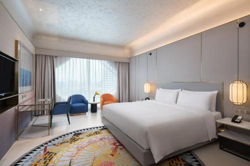 ein Schlafzimmer mit einem großen weißen Bett und ein Wohnzimmer in der Unterkunft Hangzhou Binjiang Powerlong Yijun Hotel in Hangzhou