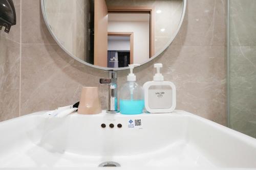 a bathroom sink with a bottle of soap and a mirror at Luxury Apartment-Vinhomes Grand Park Quận 9-Plus 2PN in Gò Công