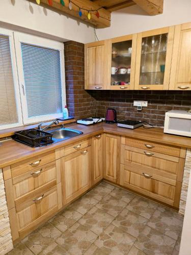 a kitchen with wooden cabinets and a sink and a microwave at Domeček Trojanovice in Trojanovice