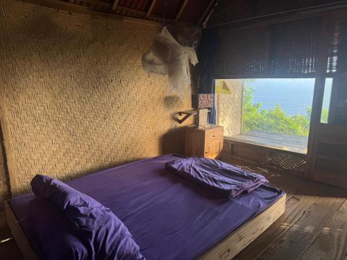 a bed with purple sheets in a room with a window at Waterfall Inn Sunset & Nature 