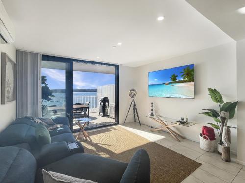 a living room with a blue couch and a view of the ocean at Coastal Chic in Batemans Bay Your Perfect Escape in Batemans Bay