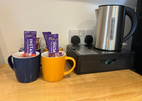 three coffee mugs sitting on a counter next to a coffee maker at The Stag Rooms in Stratford-upon-Avon