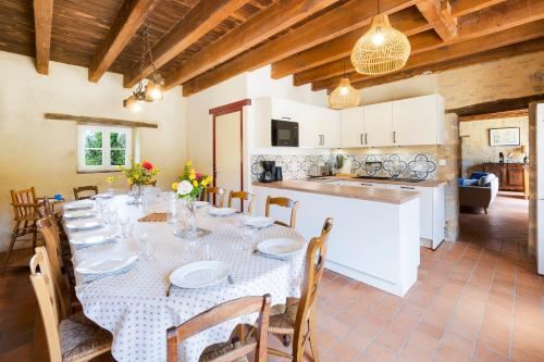 une salle à manger avec une table et une cuisine dans l'établissement La Ferme du Manoir de Kercassier à Guérande, grand gîte 15 personnes, tarif tout inclus, site exceptionnel dans grand domaine, à Guérande