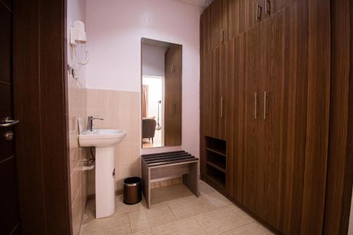 a bathroom with a sink and a wooden cabinet at Marchforte Courtyard Hotel & Suites in Ibadan
