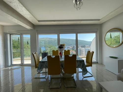 a dining room with a table and chairs and windows at Deluxe Apartment 2-rooms in Herceg-Novi