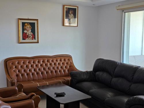 a living room with a leather couch and a table at Luxurious two bedroom Appartement résidence La Fatimide in Hiboun