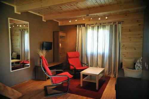a living room with two red chairs and a table at Domek nad Solinką in Bukowiec