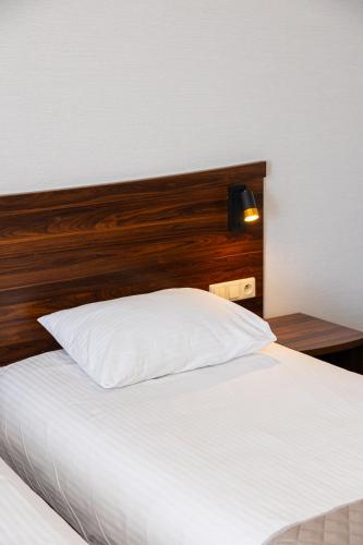 a bedroom with a white bed with a wooden headboard at Hotel Kopczyński in Dobre Miasto