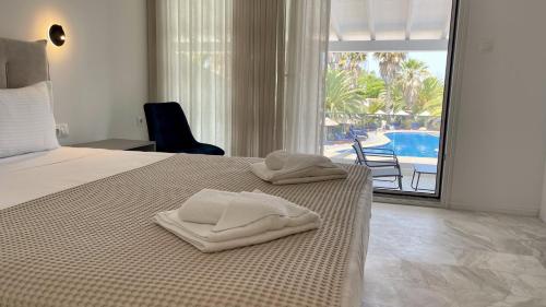 a bedroom with a bed with two towels on it at Palma Village by Greek Pride Hotels in Skála Foúrkas