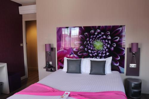 a bedroom with a large bed with a purple headboard at The Originals City - Hôtel Saint-Martial, Limoges Centre in Limoges