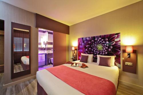 a bedroom with a large bed with a painting on the wall at The Originals City - Hôtel Saint-Martial, Limoges Centre in Limoges