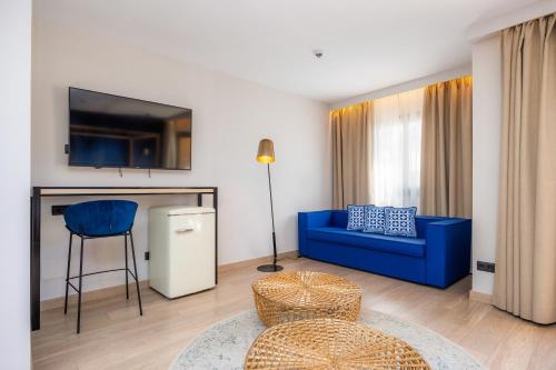 a living room with a blue couch and a tv at Marins Beach Club - Adults Only Hotel in Cala Millor