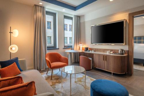 a living room with a tv and a couch and chairs at Hilton Turin Centre in Turin