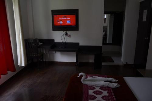 a living room with a tv on the wall and a rug at Shivlinga Tourist Complex in Uttarkāshi