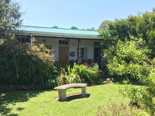 a bench sitting in the grass in front of a house at Sani Lodge & Cottages in Sani Pass