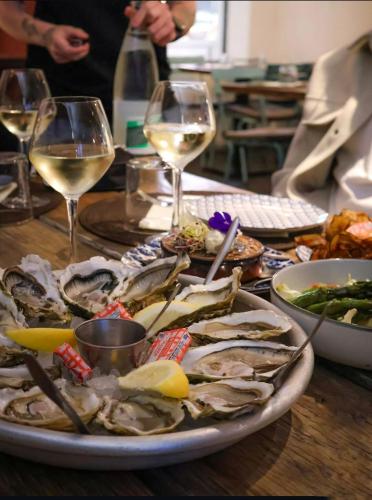 une assiette d'huîtres sur une table avec des verres de vin dans l'établissement Jolie appartement avec terrasse, vue sur canal, à 2min de la plage, à Palavas-les-Flots