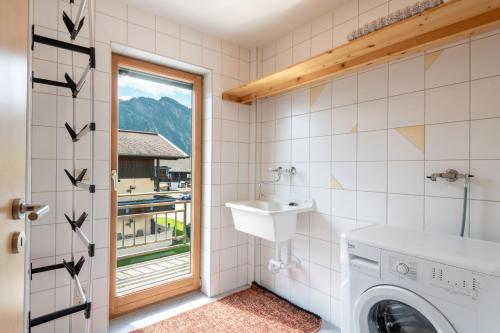 a bathroom with a washing machine and a sink at Highalp Apartments in Tannheim