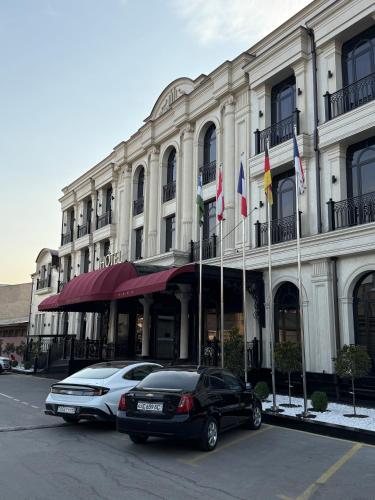 two cars parked in front of a building with flags at FRANKFORT Expo Hotel in Tashkent