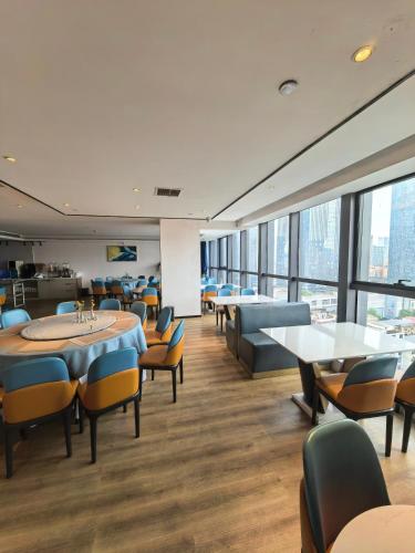a dining room with tables and chairs and windows at Changsha Feiji Hotel in Changsha