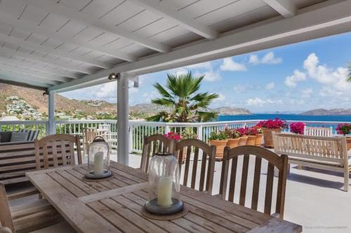 a wooden table on a porch with a view of the ocean at Fresh Summer Villa with Superb View of the Hills in Quartier de Lorient