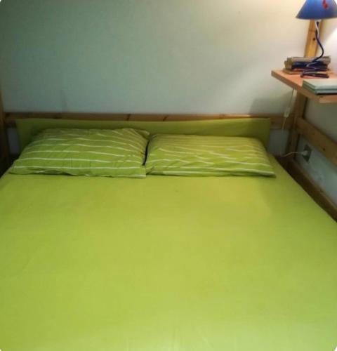 a green bed in a room with a desk at Casa Aaron - Monolocale con veranda sul mare in Stintino