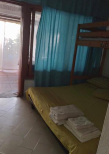 a bedroom with a bed with a blue curtain and a window at Casa Aaron - Monolocale con veranda sul mare in Stintino
