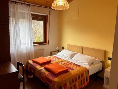 a bedroom with a bed with two orange pillows on it at RESIDENZA VALLE VIGEZZO in Santa Maria Maggiore
