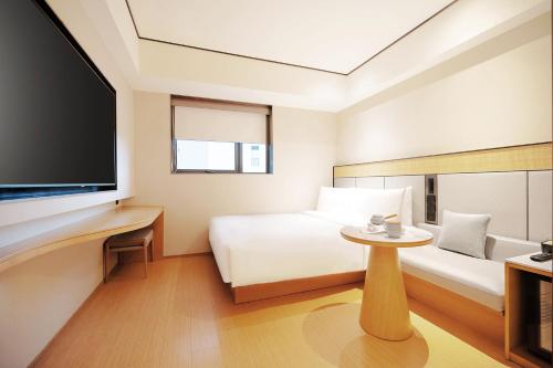 a hotel room with a bed and a tv at Ji Hotel Orchard Singapore in Singapore