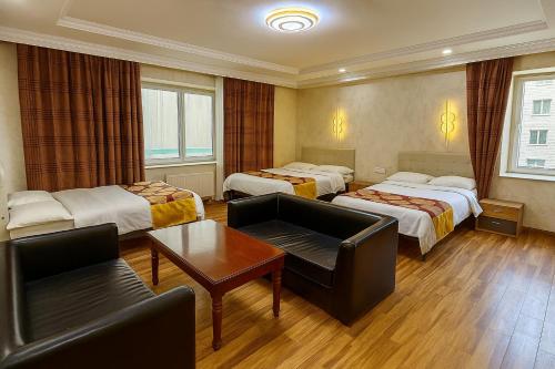 a hotel room with three beds and a couch at Evergreen Hotel in Ulaanbaatar