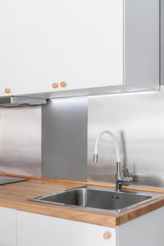a stainless steel sink in a kitchen with white cabinets at Lumahaus Chamber Palaiologou in Thessaloniki
