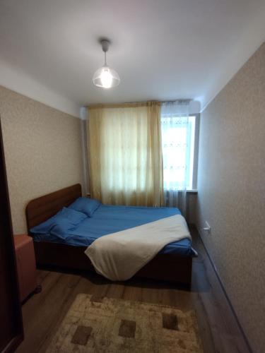 a bedroom with a blue bed and a window at Room in apartment, bolme in Almaty