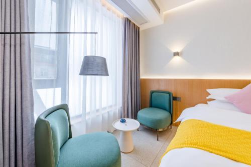 een hotelkamer met een bed en twee stoelen en een raam bij Zhangjiajie Tianmen Mountain Cableway High-end B&B in Zhangjiajie