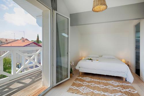 ein Schlafzimmer mit einem Bett und einem Balkon in der Unterkunft L'Arcachonaise in Arcachon
