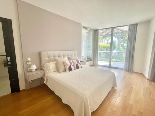 a white bedroom with a white bed with two pillows at Modern villa in gated complex Sierra Blanca Marbella in Marbella