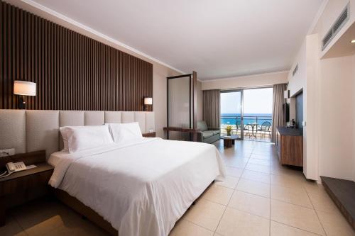 a hotel room with a bed and a view of the ocean at KRESTEN ROYAL Euphoria Resort in Kallithea Rhodes