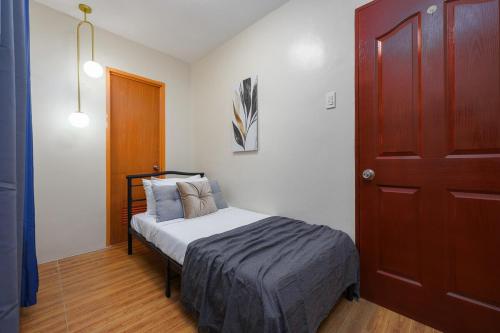 a small bedroom with a bed and a wooden door at Furnished 3BR Townhouse Near Cebu IT Park with Parking, Fast WiFi, Netflix and More in Cebu City
