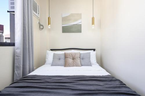 a bedroom with a bed with white sheets and pillows at Furnished 3BR Townhouse Near Cebu IT Park with Parking, Fast WiFi, Netflix and More in Cebu City