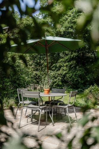 a table and chairs with a green umbrella at de Wever Lodge in Otterlo