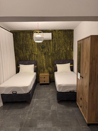 two beds in a room with green wallpaper at Uyar Pansiyon & Apart in Bodrum City