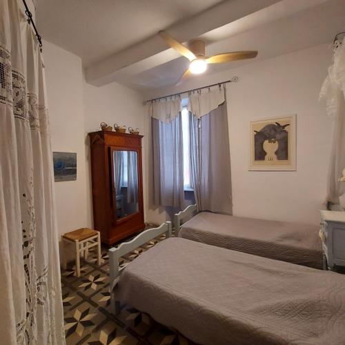 une chambre avec deux lits et un ventilateur de plafond dans l'établissement Le Patio Des Cigales, à Roquefort-des-Corbières