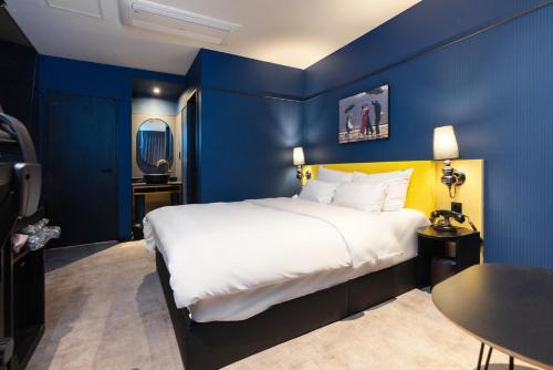 a bedroom with a large bed with blue walls at Hotel Ippda Wonju in Wonju