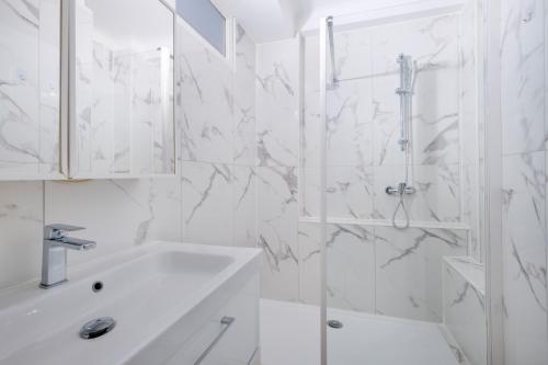une salle de bain blanche avec une douche et un lavabo dans l'établissement Evasion Cannoise, à Cannes