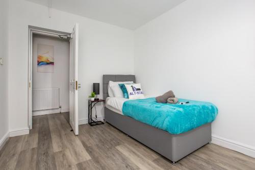 a bedroom with a bed with a blue blanket at Manygates by Alt-Stay - Huge 4 Bed Apartment Contractor and Relocation Accommodation Near Wakefield near City Centre and M1 J39 with Ample Off Road Parking, Kitchen, Washer Dryer, Smart TV and Wi Fi - Long Stay Ready with Weekly and Monthly Rates in Wakefield