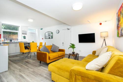 a living room with yellow furniture and a kitchen at Manygates by Alt-Stay - Huge 4 Bed Apartment Contractor and Relocation Accommodation Near Wakefield near City Centre and M1 J39 with Ample Off Road Parking, Kitchen, Washer Dryer, Smart TV and Wi Fi - Long Stay Ready with Weekly and Monthly Rates in Wakefield