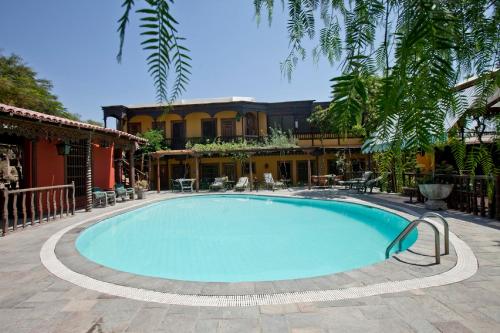 a pool in a courtyard with a building in the background at Hotel & Hacienda El Carmelo in Ica