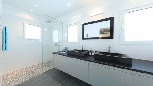 a white bathroom with two sinks and a mirror at Dazzling Villa with Heated Swimming Pool in Grand Fond