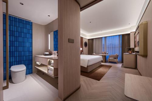 a hotel room with a bed and a bathroom at Orange Crystal Qingdao Liaoyang West Road Guoxin Sports Center Hotel in Qingdao