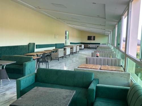 a restaurant with green couches and tables and windows at la maison d'autre Nadia in Sefrou