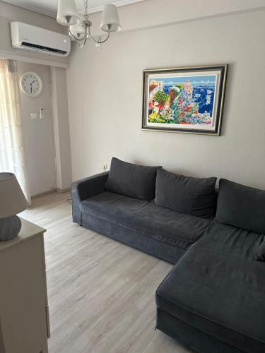 a living room with a blue couch and a clock at Apartment Antikyra in Antikyra